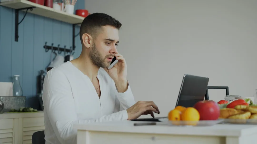 Man on the phone to his provider with a laptop open at the table
